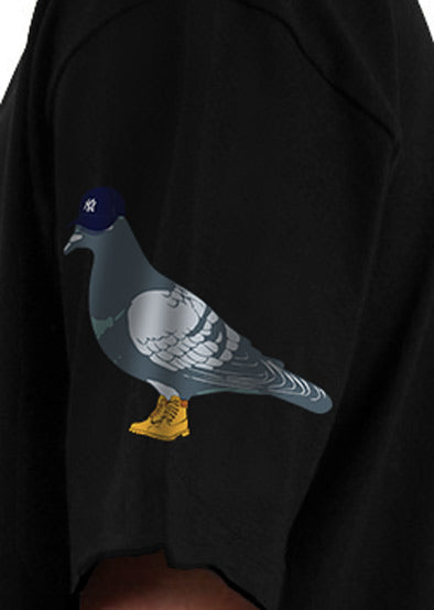 A close-up view of a black tshirt featuring a minimalistic full color pigeon design on the side sleeve.