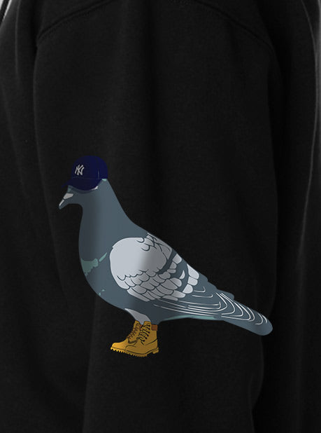 A close-up view of a black sweatshirt featuring a minimalistic full color pigeon design on the side sleeve.